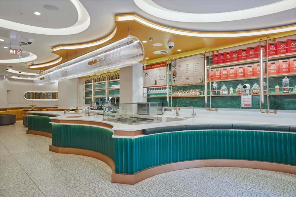 Contemporary Haidilao Hot Pot interior featuring curved marble counters, vibrant green accents, and illuminated shelving, Piccadilly Circus, London.